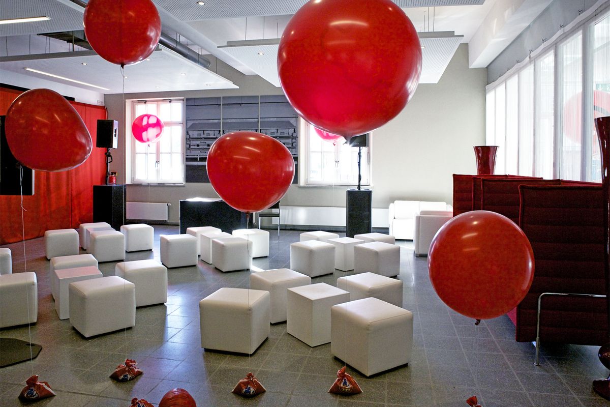 Dekorierter Raum mit roten Luftballons und weißen Hockern